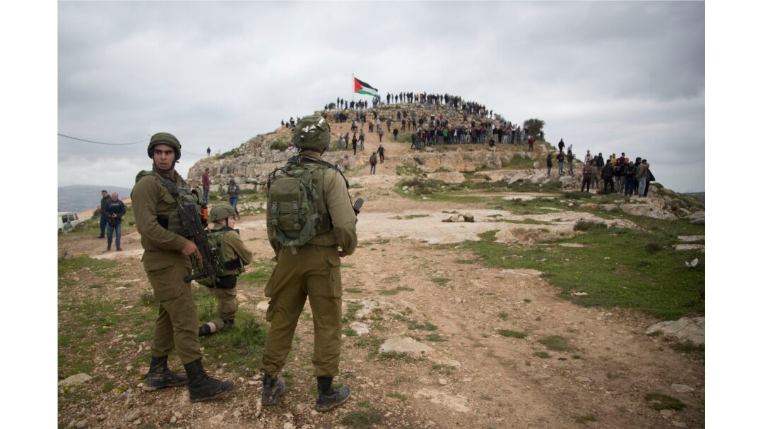FILE - Israeli soldiers take position as Palestinian demonstrators gather during a protest against expansion of Israeli settlements, in the West Bank village of Beita near Nablus, March 2, 2020.