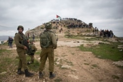 Israeli soldiers take position as Palestinian demonstrators gather during a protest against expansion of Israeli settlements, in the West Bank village of Beita near Nablus, March 2, 2020.