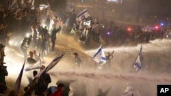Policías israelíes emplean un cañón de agua para dispersar a los manifestantes que cortan una autopista durante una protesta contra los planes del primer ministro, Benjamin Netanyahu, de reformar el sistema judicial del país, en Tel Aviv, Israel, el lunes 27 de marzo de 2023.