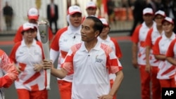 Indonesian President Joko "Jokowi" Widodo, center, holds the Asian Games torch as he runs during an independence day ceremony at Merdeka Palace in Jakarta, Indonesia, Aug. 17, 2018. Critics say the president is growing increasingly authoritarian.