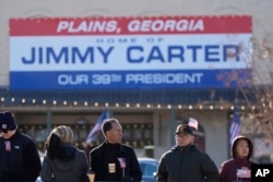 People wait for a funeral procession for former President Jimmy Carter to move through downtown Plains, Georgia, Jan. 4, 2025.