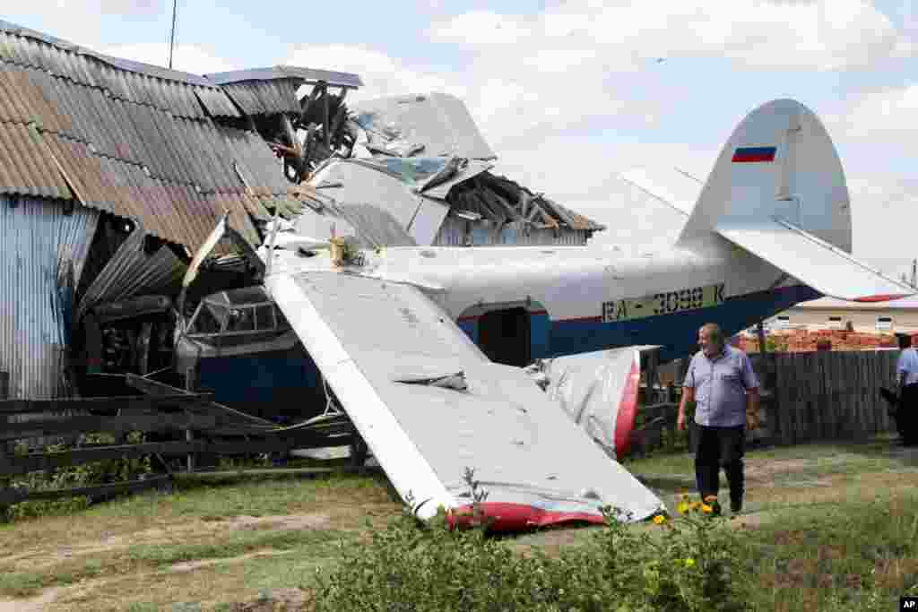A man walks at the scene of a small private plane that crashed into a house in Novoshchedrinskaya, Russia. Four people were injured, including the pilot.
