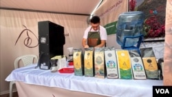 Faiber Trujillo, en una vitrina de exposición con las marcas de café elaboradas en la trilladora del ETCR El Oso en Gaitania, Planadas, Tolima, el 1 de noviembre de 2024. [Javier Hernández, VOA] 