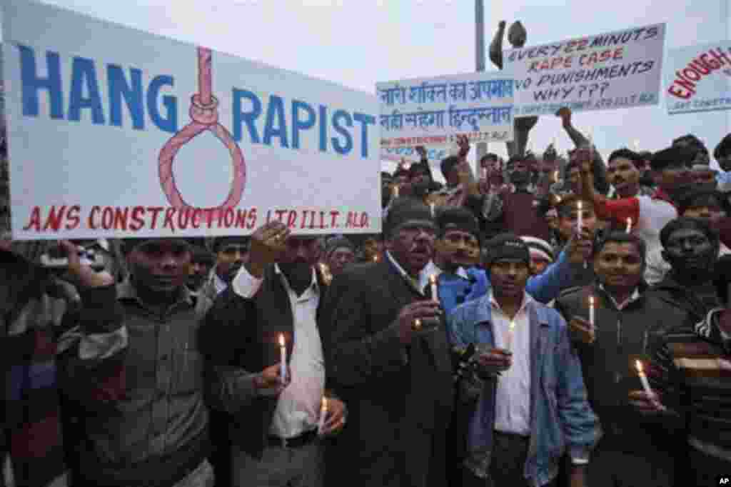 Indians hold candles and mourn the death of a young woman who was recently gang-raped in a moving bus in New Delhi, in Allahabad, India, Sunday, Dec. 30, 2012. The young woman was cremated Sunday amid an outpouring of anger and grief by millions across the country demanding greater protection for women from sexual violence. Placard, center, reads "India will no longer tolerate insult to women." (AP Photo/Rajesh Kumar Singh)