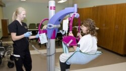 A nursing student at the University of Missouri practices using a lift that helps transfer patients from one chair to another