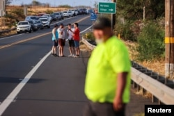 La gente se alinea en una barricada de la policía mientras intenta obtener información mientras esperan para tener acceso al oeste de Maui, que ha sido aislado por incendios forestales, que se cree que destruyeron gran parte de la ciudad histórica de Lahaina, en Kahului, Hawái, EEUU, el 9 de agosto de 2019. 2023. REUTERS/Marco García