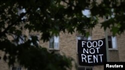 Makeshift banners displaying messages of protest contesting the ability to pay for rent hang in the window of an apartment building in the Columbia Heights neighborhood in Washington, May 18, 2020. 