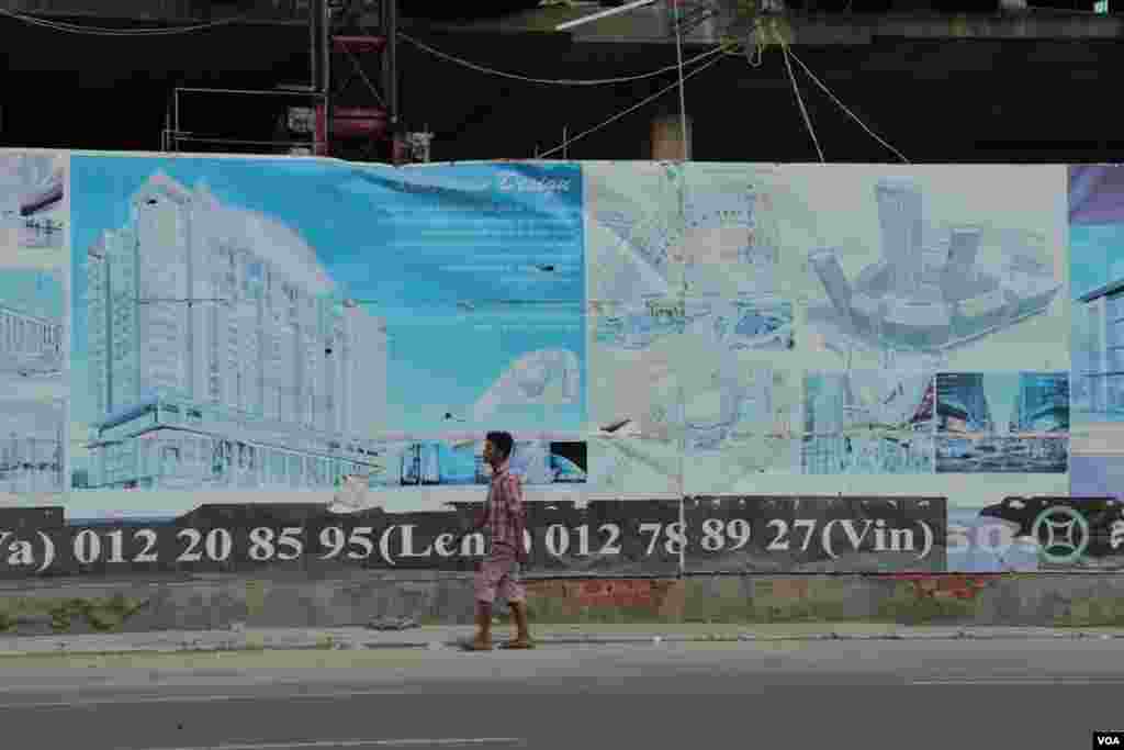 A passenger walks past an advertisement for Olympia City near its construction site. on September 29, 2014. (Nov Povleakhena/VOA Khmer) 