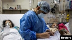 Rohan Aggarwal, 26, seorang dokter residen yang merawat pasien yang menderita COVID-19, menulis catatan selama shift 27 jamnya di Rumah Sakit Keluarga Suci di New Delhi, India, 1 Mei 2021. (Foto: Reuters)