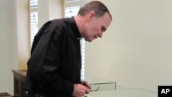 The Very Rev. David M. O'Connell examines the etching he discovered in a bathroom cabinet