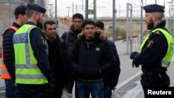 FILE - Swedish police officers speak to a group of people at the Hyllie train station near Malmo, Sweden, Nov. 12, 2015. 