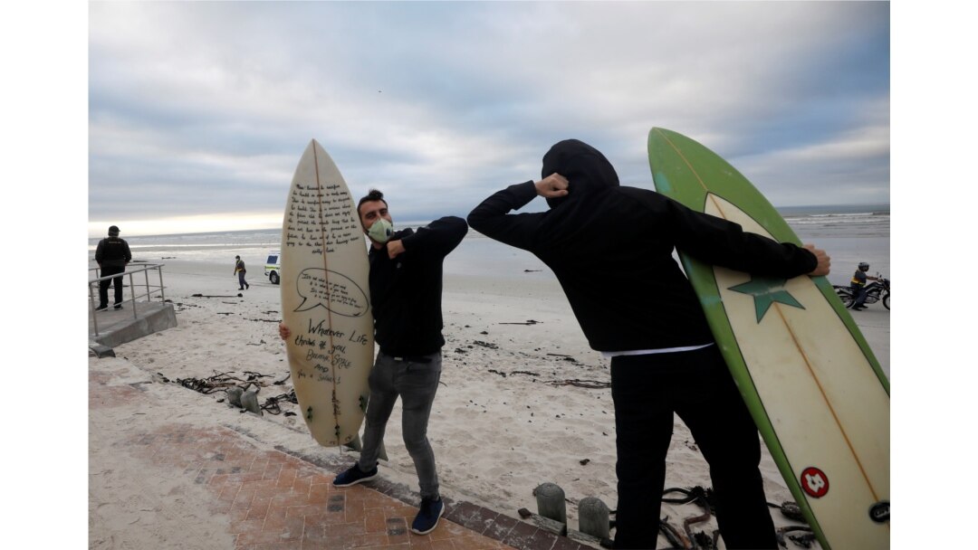 FILE - Surfers bump elbows as they protest against the nationwide lockdown regulations that allow exercise but not water activities, amid the coronavirus disease (COVID-19) outbreak, at Muizenberg beach in Cape Town, South Africa, May 5, 2020.