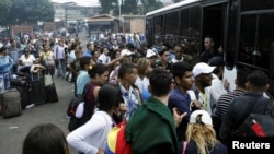 Migrantes venezolanos tratan de abordar un bus que los lleve a la frontera con Colombia desde la frontera San Cristóbal, en Venezuela.