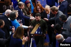 Ukraine's President Volodymyr Zelenskyy carries a U.S. flag presented to him by U.S. House Speaker Nancy Pelosi (D-CA) during a joint meeting of the U.S. Congress in the House Chamber of the U.S. Capitol in Washington, Dec. 21, 2022.