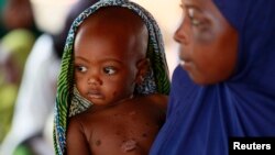 Mother and child wait to see a doctor in Nigeria.