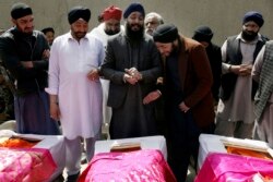 FILE - Afghan Sikh men mourn fellow believers killed by an Islamic State gunman, during their funeral in Kabul, March 26, 2020.