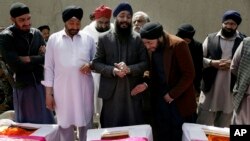 FILE - Afghan Sikh men mourn fellow believers killed by an Islamic State gunman, during their funeral in Kabul, Afghanistan, March 26, 2020. 