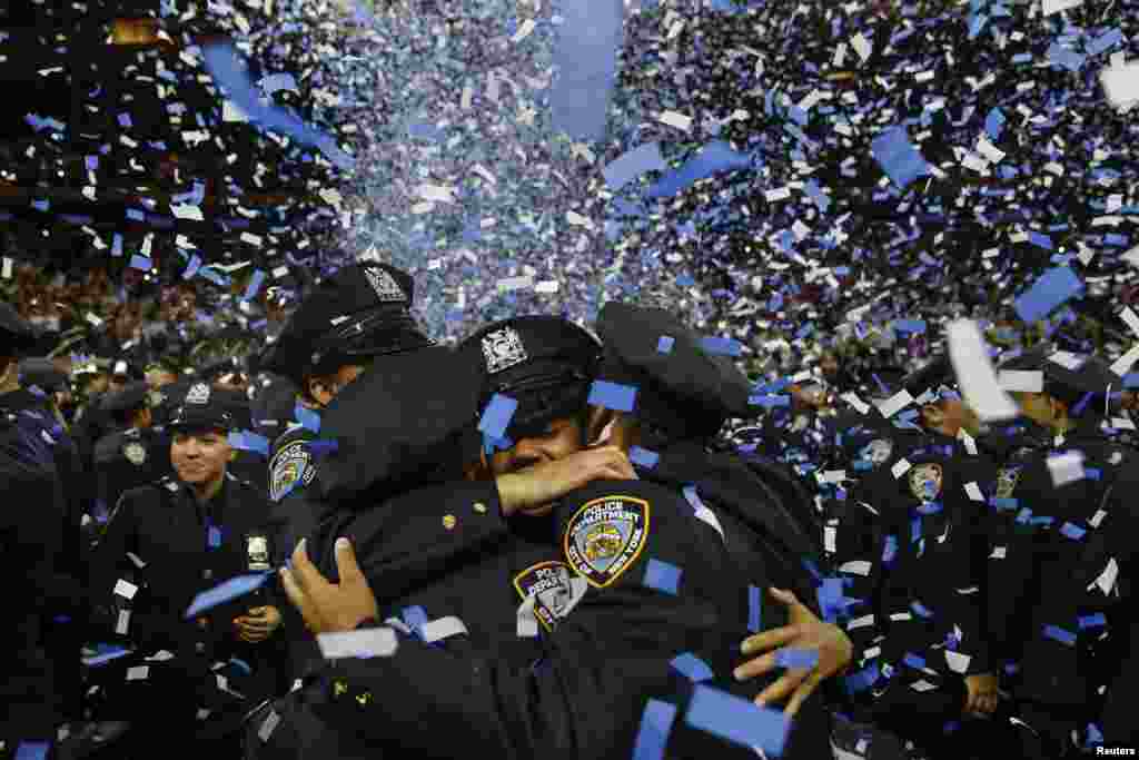 Members of the class of the New York City Police Academy embrace during their graduation ceremony at Madison Square Garden in New York.