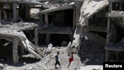 People walk amidst the rubble of damaged buildings in Deraa, Syria, July 15, 2017. 