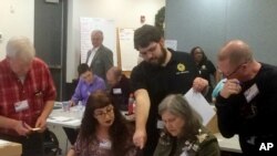 维吉尼亚州纽波特纽斯的选务官员在州众议员选举的重新计票过程验看电脑无法扫描的选票。（2017年12月19日）