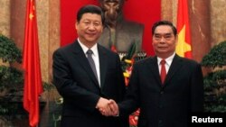 FILE - China's Vice President Xi Jinping (L) poses for a photo with Vietnam's Communist Party's Senior Politburo member Le Hong Anh in front of a bust of late Vietnamese revolutionary leader Ho Chi Minh at the Presidential Palace in Hanoi, Dec. 21, 2011.