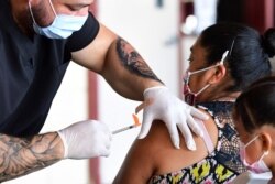 FILE - The Pfizer COVID-19 vaccine is administered at a mobile clinic in an East Los Angeles neighborhood, which has shown lower vaccination rates, especially among the young, July 9, 2021.