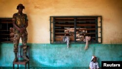 An African Union peacekeeper stands on a chair as a small child sits of the floor at an Islamic center where Peul refugees have sought protection in Bangui, Central African Republic, Dec. 18, 2013.