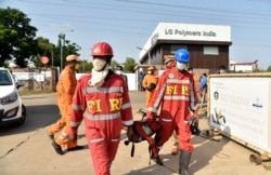 Firefighters walk with oxygen cylinders outside LG Polymers plant, the site of a chemical gas leak, in Visakhapatnam, India, May 7, 2020. Synthetic chemical styrene leaked from the industrial plant in southern India.