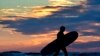 A surfer heads out to ride the waves on another unusually mild morning at Old Orchard Beach, Maine.