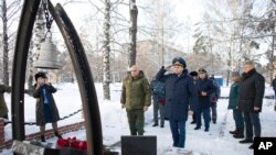 Kemerovo Governor Sergei Tsivilyov, center left, and Russian Deputy Prosecutor General Dmitrii Demeshin, center, lay flowers at the memorial to honor fallen rescuers in Gramoteino village, Kemerovo region of southwestern Siberia, Russia, Nov. 26, 2021.