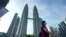 မလေးရှားနိုင်ငံ Kuala Lumpur မြို့ရဲ့ Twin Towers အရှေ့မှာ တွေ့ရတဲ့ နှာခေါင်းစည်းတပ်ထားသည့် အမျိုးသမီး တဦး (မတ် ၁၈၊ ၂၀၂၀)