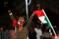 A woman flashes the victory sign during the first anniversary of the start of the uprising that toppled long-time ruler Omar al-Bashir, at the Friendship Hall in Khartoum, Sudan, Dec. 25, 2019.