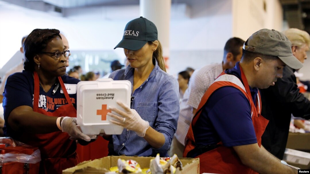 FILE - First lady Melania Trump helps a volunteer hand out meals during a visit with flood survivors of Hurricane Harvey at a relief center in Houston, Texas, Sept. 2, 2017.