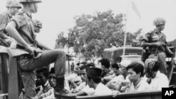 Members of the Youth Wing of the Indonesian Communist Party are guarded by soldiers as they are taken by an open truck to prison in Jakarta after they were rounded up by the army following a crackdown on communists after an attempted coup, Oct. 30, 1965.