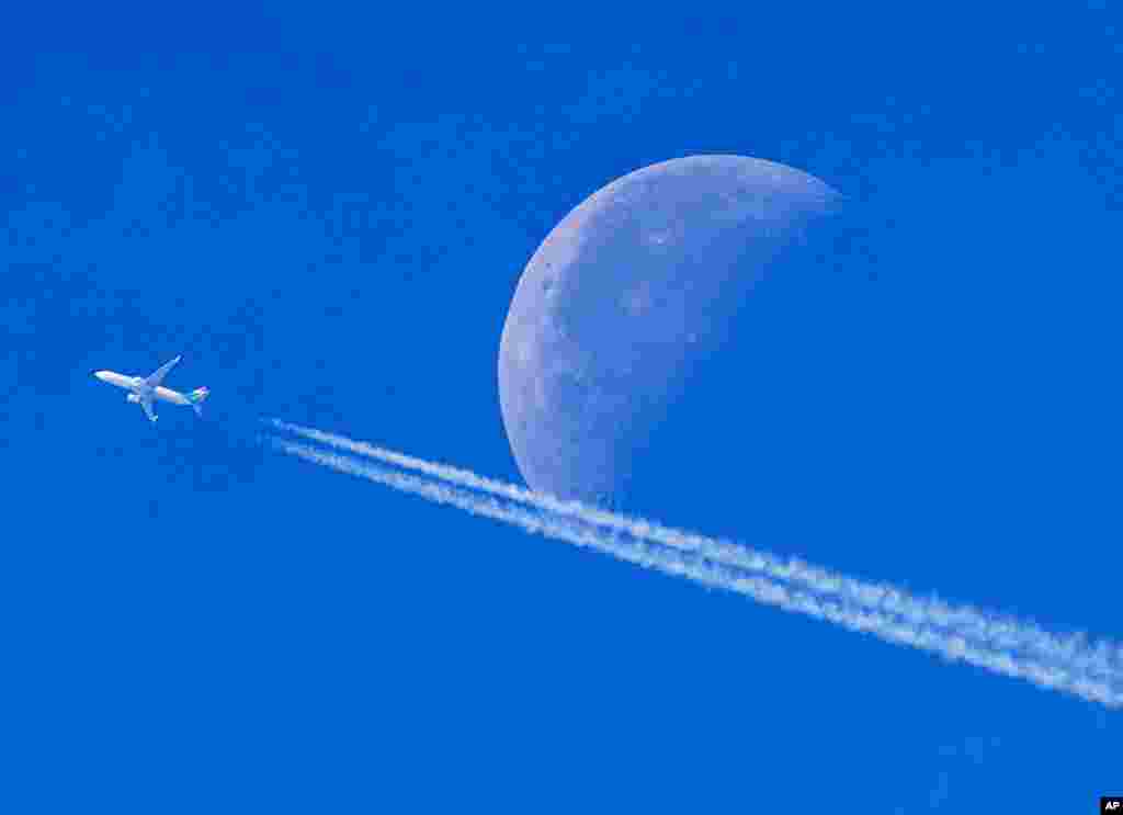 An aircraft passes the setting moon over Frankfurt, Germany.