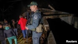 Kosovski policajac i lokalni stanovnici stoje u blizini oštećenog kanala na severu Kosova, u Varagama, Kosovo, 29. novembar 2024. (Foto: Reuters/Valdrin Kshemaj)