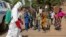 Children watch as a health worker sprays disinfectant outside a mosque in Bamako, Mali, Nov. 14, 2014.
