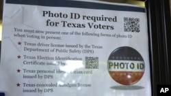 FILE - A sign in a window tells of photo ID requirements for voting at a polling location in Richardson, Texas, Nov. 5, 2013. The Trump administration says Texas has rid its voter ID law of any discriminatory effects and is asking a judge who once compare