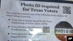 FILE - A sign in a window tells of photo ID requirements for voting at a polling location in Richardson, Texas, Nov. 5, 2013. The Trump administration says Texas has rid its voter ID law of any discriminatory effects and is asking a judge who once compared the measure to a "poll tax" to not take further action.