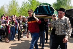 Men carry a coffin with the body of Elvira Ignatieva, a teacher who was killed in a shooting at a school on Tuesday, in Kazan, Russia, May 12, 2021.