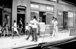 FILE - Two men carry furniture looted from a store in Newark, New Jersey, July 14, 1967.