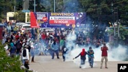 FILE - Some engulfed in teargas, students and other protestors confront riot police outside the university during a protest against President Juan Orlando Hernandez in Tegucigalpa, Feb. 5, 2018. 