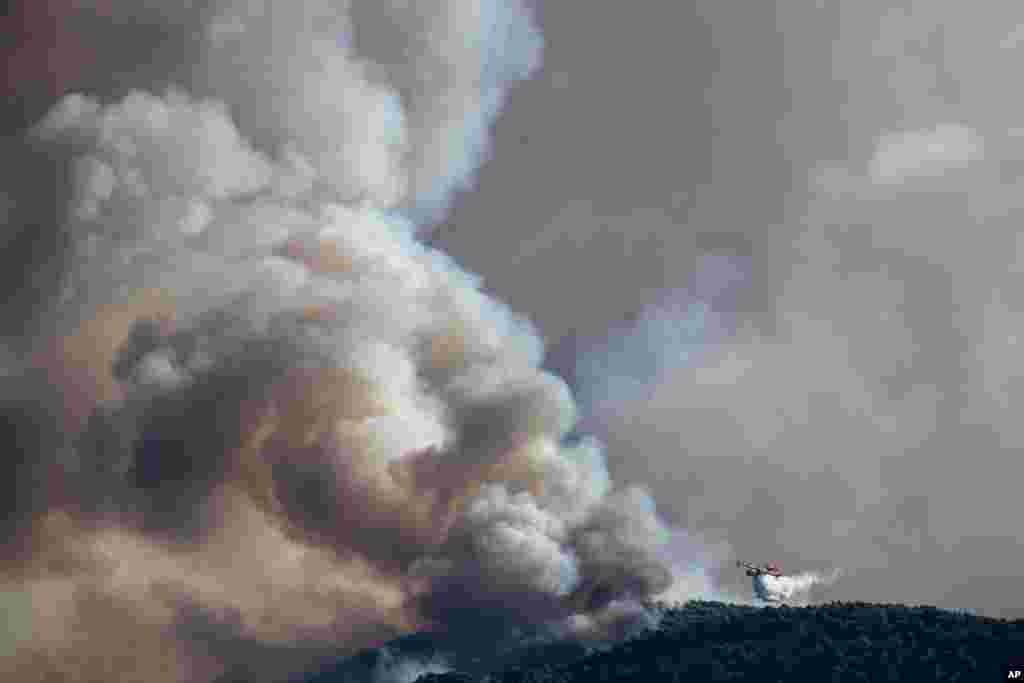 عکسی از آتش‌سوزی در منطقه کورینتوس در ۸۰ کیلومتری آتن در یونان. نیروهای امداد با هواپیمای مخصوص در تلاش برای خاموش کردن آتش هستند.