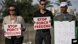 Israeli Arab supporters of Mohammed Allan, a Palestinian prisoner on a hunger strike, hold signs during a support rally outside Barzilai hospital, in the costal city of Ashkelon Israel. Israel passed a law to force feed hunger strikers by a slim margin in July and elicited harsh criticism, August 11, 2015.