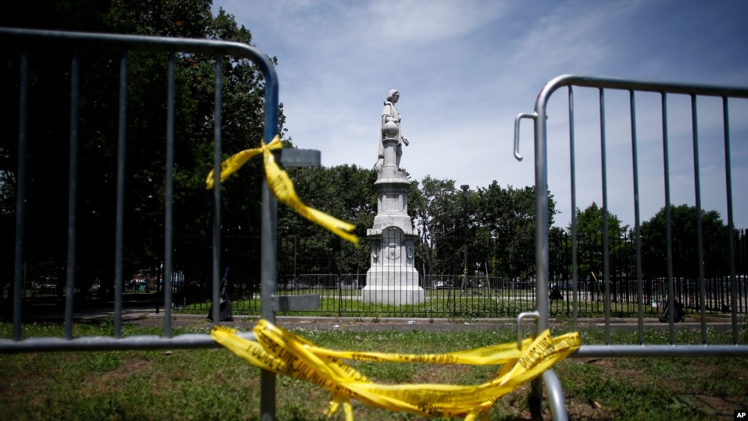FILE - A statue of Christopher Columbus is seen behind barricades at Marconi Plaza, in Phalidelphia, Pennsylvania, June 15, 2020. A similar statue of Columbus was toppled by protesters in Baltimore, Maryland, July 4, 2020.