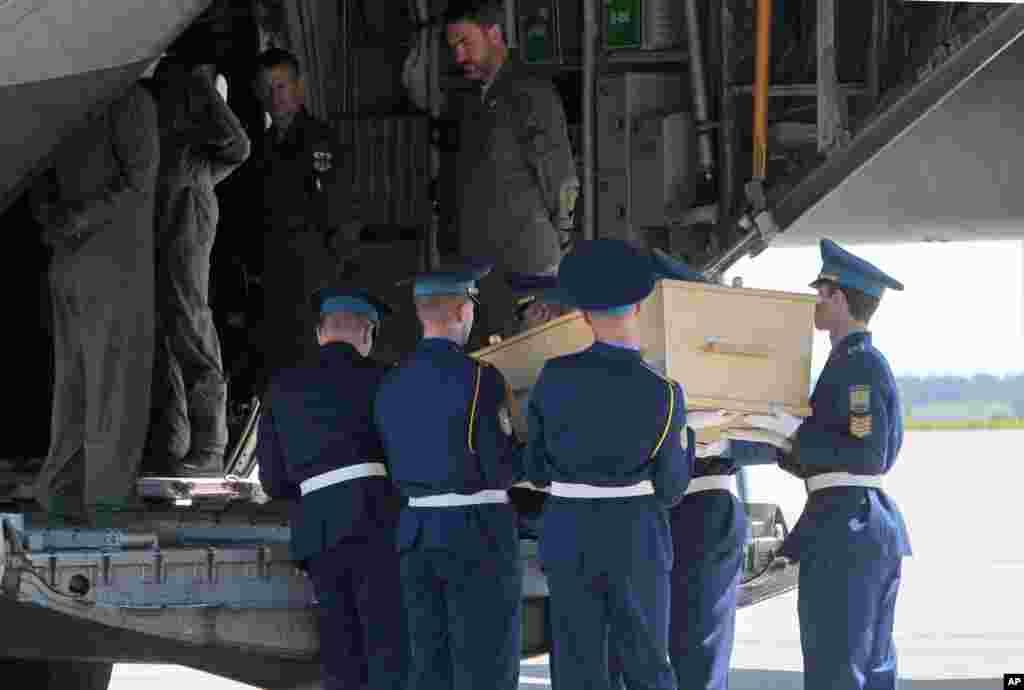 Dutch cargo plane crew members wait as Ukrainian honor guards load a coffin with the body of a Malaysian Airlines plane passenger on to a plane at the Kharkiv airport, Ukraine.