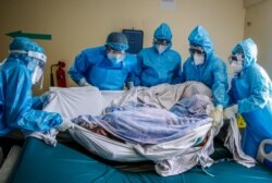 FILE - A medical team rolls a coronavirus patient from a bed onto a stretcher in the COVID-19 intensive care unit at Kenyatta National Hospital, in Nairobi, Kenya, April 14, 2021.