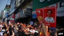 2021年2月6日缅甸仰光的抗议活动中，一名示威者手举国务资政昂山素季和总统温敏的头像。