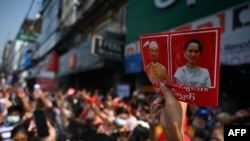 A protester holds up a sign with the images of detained Myanmar civilian leader Aung San Suu Kyi, right, and president Win Myint during a demonstration against the military coup in Yangon, Myanmar, on Feb. 6, 2021.