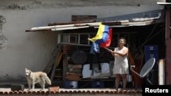 Una mujer ondea una bandera venezolana durante la procesión del Nazareno de San Pablo en el barrio marginal de Antimano a pesar de una cuarentena en todo el país debido al brote de la enfermedad del coronavirus (COVID-19) en Caracas, Venezuela.